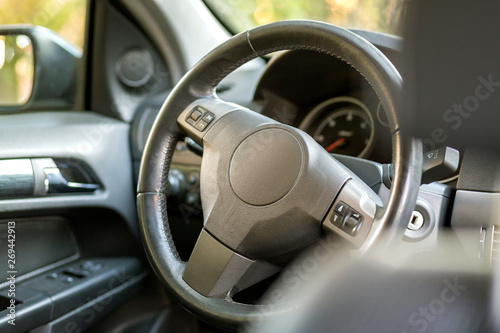 Modern expensive car black luxurious interior. Steering wheel, dashboard, windshield and mirror. Transportation, design, modern technology concept.