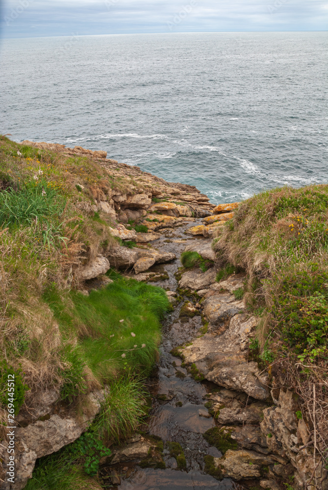 Top view of stream between rocks that flows into the sea in Ruiloba, Cantabria, Spain, Europe