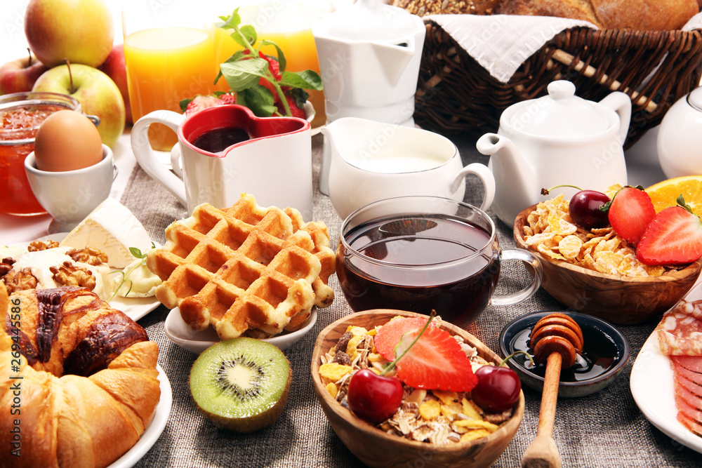 Huge healthy breakfast on table with coffee, orange juice, fruits, waffles and croissants. Good morning concept.