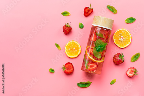 Strawberry infused water, cocktail, lemonade or tea. Summer iced cold drink with strawberry, lemon and lef of mint on pink background. Flat lay. Top view.