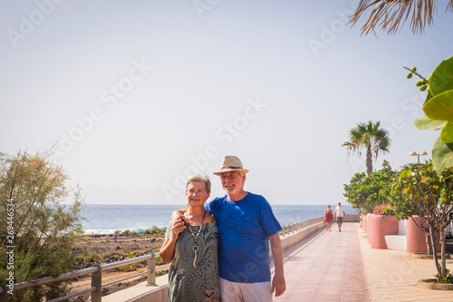 Happiness in retired lifestyle people with caucasian senior aged couple walking happy  hugging eachother with love - forever concept and enjoying outdoor leisure activity photo