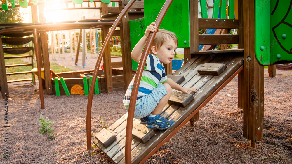 Portrait of adorable 3 years old boy climbing on ladder on the children palyground at park Portrait of adorable 3 years old boy climbing on ladder on the children palyground at park