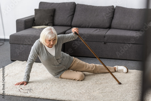 Fotografie suffering senior woman with heart attack on carpet