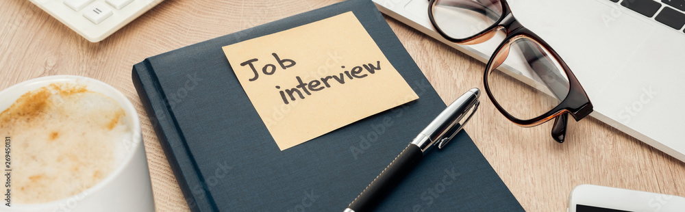 panoramic shot of notebook with job view lettering on sticky note on wooden surface with pen, glasses and cup of coffee