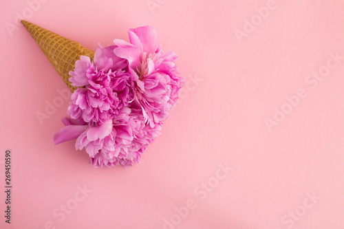 Ice cream cone with pink peonies on the pink background.Top view.Copy space.Spring flowers concept.