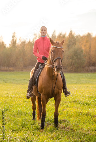 portrait of young woman riding red horse in autumn field © vprotastchik