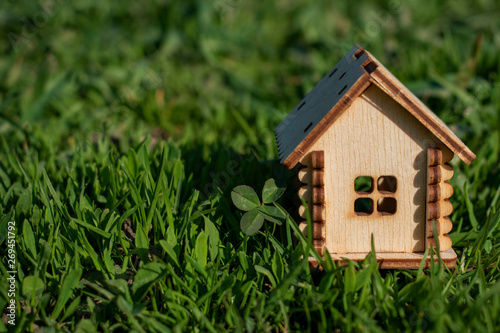 Toy wooden house on the bright grass in sunny weather. Copy space. Real estate concept, business loan financing concept, new house concept. © Anastasiya