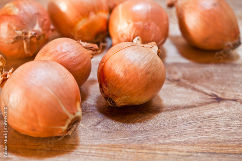 Fototapeta Naklejka Na Ścianę i Meble -  Fresh organic onions heap closeup on rustic wooden background.