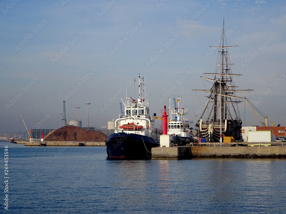 view of a tugboat moored in the harbor next to fishing boats