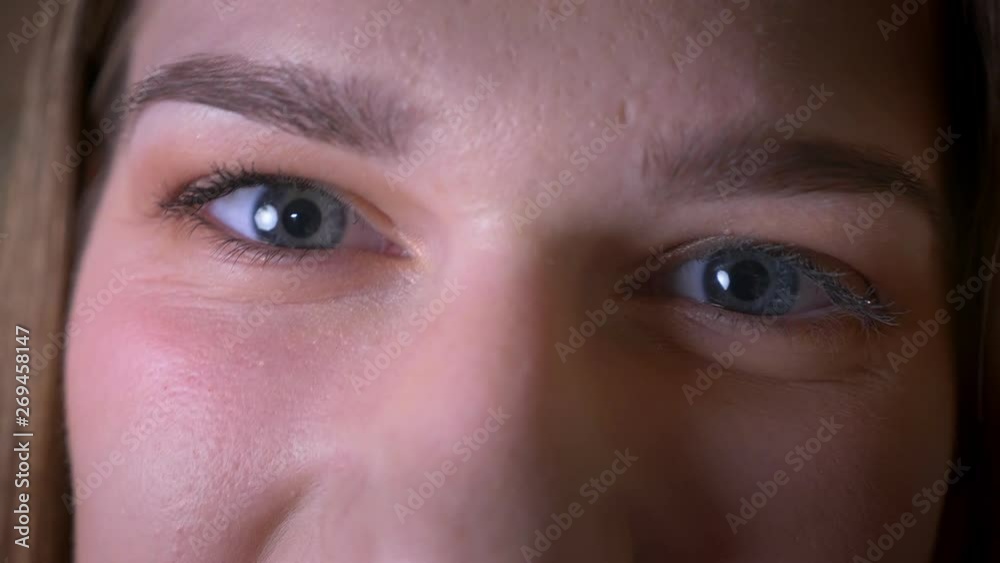 Closeup shoot of young brunette female face with eyes looking at camera with smiling facial expression Closeup shoot of young brunette female face with eyes looking at camera with smiling facial expression