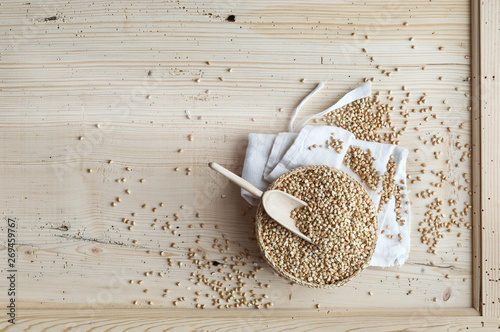 Organic buckwheat, whole grains in woven bowl on wood, from above