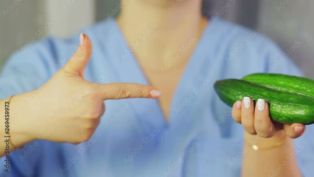 In female hands green cucumbers. A hand is pointing at them In female hands green cucumbers. A hand is pointing at them