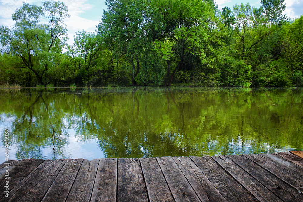 Lake with forest and reflection from a wooden pier Lake with forest and reflection from a wooden pier