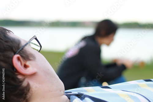 Lying man on the beach looking at an Asian woman