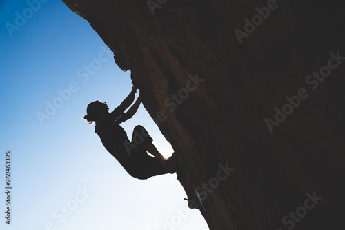 Silhouette of climber climbing up a rock