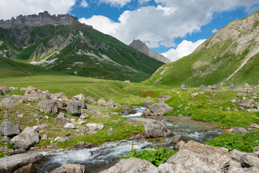 Picturesque view of the rocky mountain range towering above the emerald river.