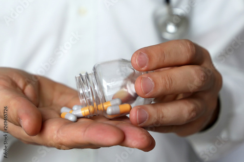 Doctor with bottle of pills, man with stethoscope giving medication in capsules. Concept of dose of drugs, vitamins, medical prescription, pharmacy, flu treatment