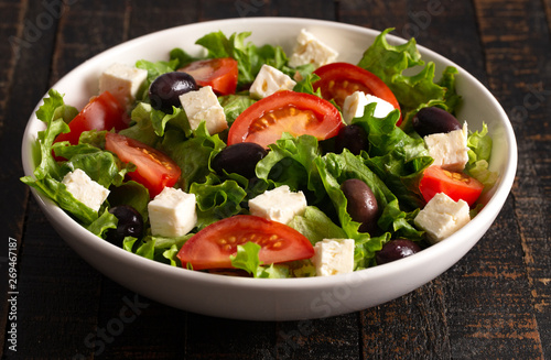 Greek Salad with Olives Tomatos and Feta Cheese on a Rustic Wood Table