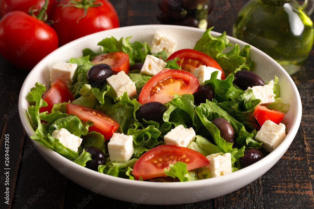 Greek Salad with Olives Tomatos and Feta Cheese on a Rustic Wood Table