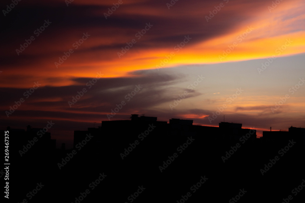 Colorful dark dramatic sky with cloud at sunset and builings in the darkness