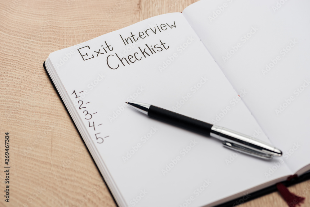 notebook with exit interview checklist lettering and numbers on wooden table with pen notebook with exit interview checklist lettering and numbers on wooden table with pen