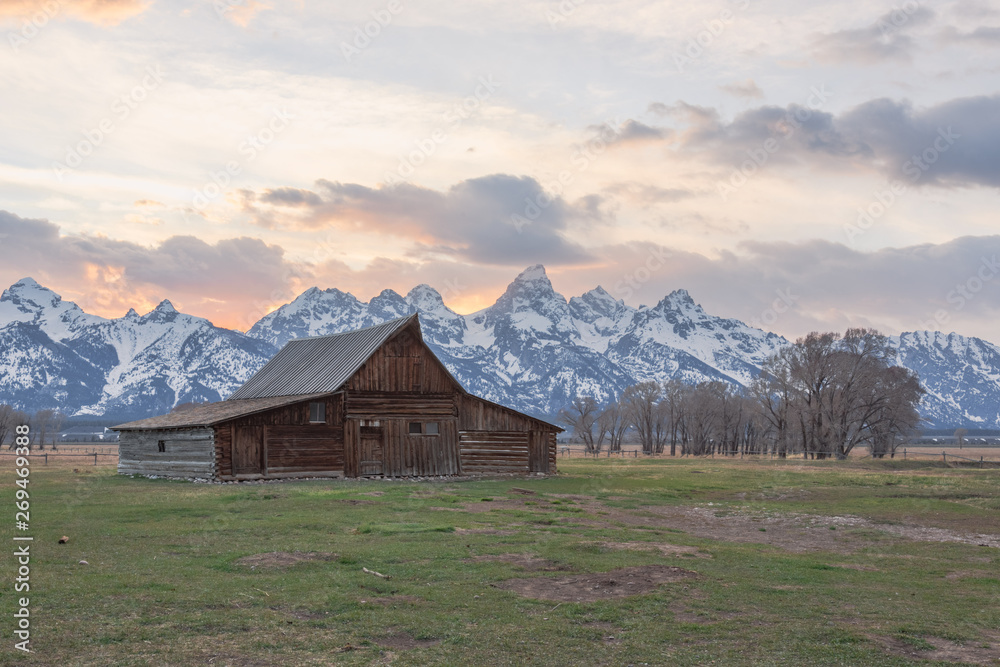 Infamous T.A. Moulton Barn during sunset in Mormon Row, Grand Teton National Park, Wyoming. Features backlit Teton peaks within the panorama. Infamous T.A. Moulton Barn during sunset in Mormon Row, Grand Teton National Park, Wyoming. Features backlit Teton peaks within the panorama.