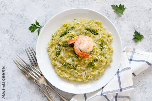 Italian risotto with asparagus and shrimps in plate on light background. Top view with copy space.