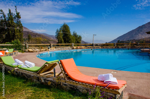 colored loungers by the pool. pool against the backdrop of the mountains. orange sun loungers. white towels
