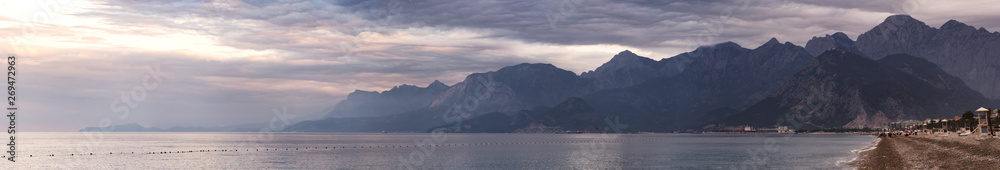 Panorama of Konyaaltı Beach against the backdrop of mountains and sunset sky
