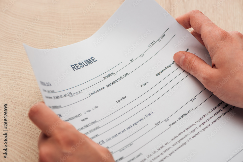 Obraz premium cropped view of recruiter holding resume template in hands