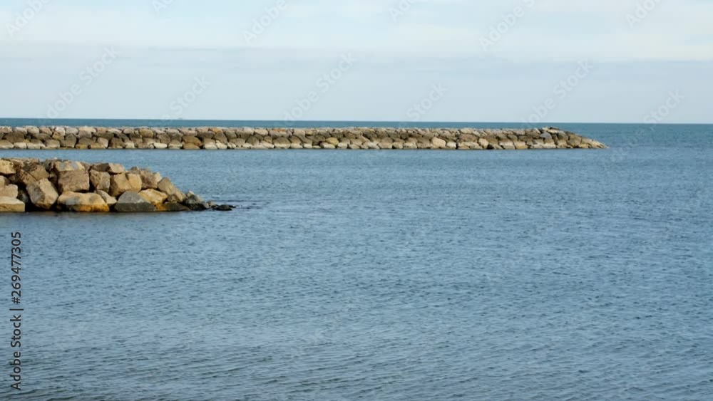 View of the breakwater of stone in the sea. Cloudy day. View of the breakwater of stone in the sea. Cloudy day.