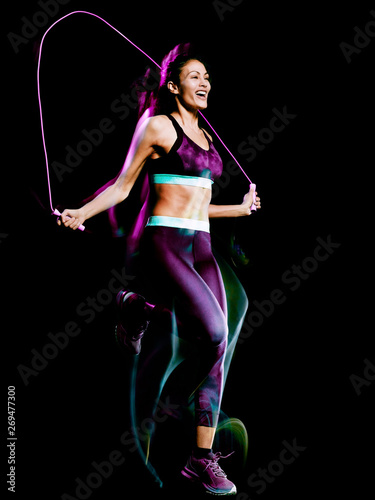 one beautiful caucasian mixed race woman exercising  jumping rope fitness exercises in studio isolated on black background © snaptitude