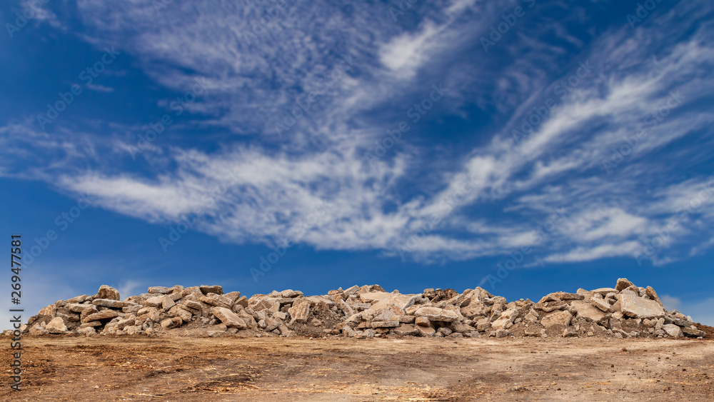 Concrete debris pile with cloudy sky in the background.