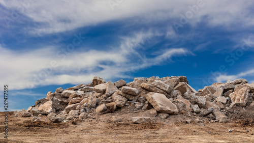 Concrete debris pile with cloudy sky in the background.