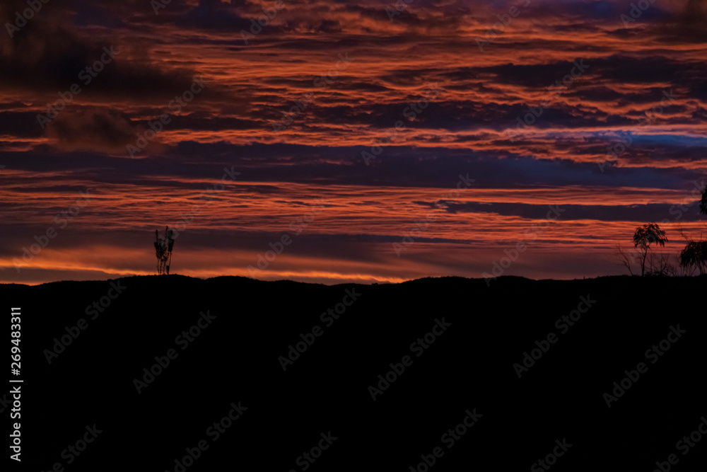 Vibrant red sunset and clouds across a Gully.