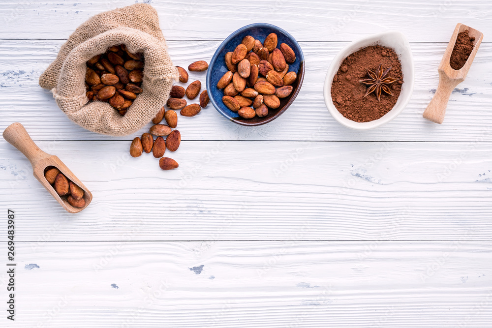 Cocoa powder and cacao beans on wooden background.