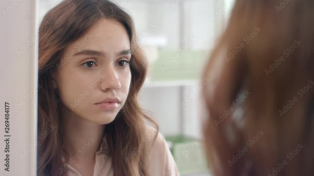 Beautiful woman plucking eyebrows with tweezers in mirror at bathroom Beautiful woman plucking eyebrows with tweezers in mirror at bathroom