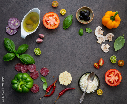 The ingredients for homemade pizza on dark stone background.