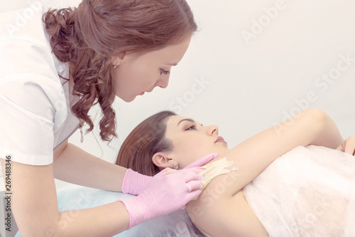 sugar depilation. shugaring procedure the master puts a shugaring paste on the skin to the client girl for depilation