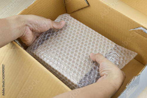 hand of man hold Bubbles covering the box by bubble wrap for protection product