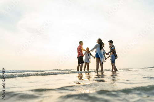 A group of male and female friends who play fun on the sea beach amid the sunset.