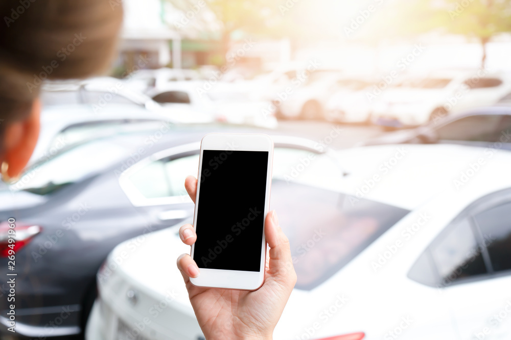 Hand holding smartphone with black screen at car park