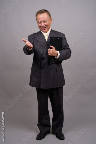 Portrait of mature Asian businessman against gray background