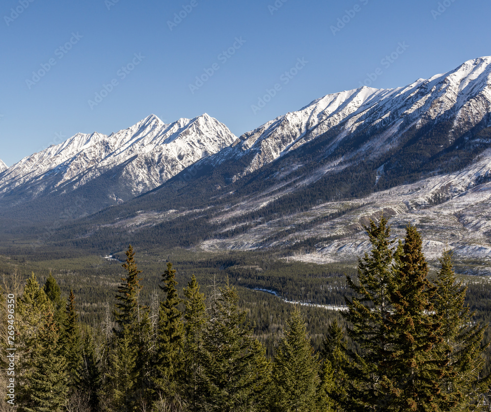 snow mountains peaks and forest landscape under sunlight early spring as background.