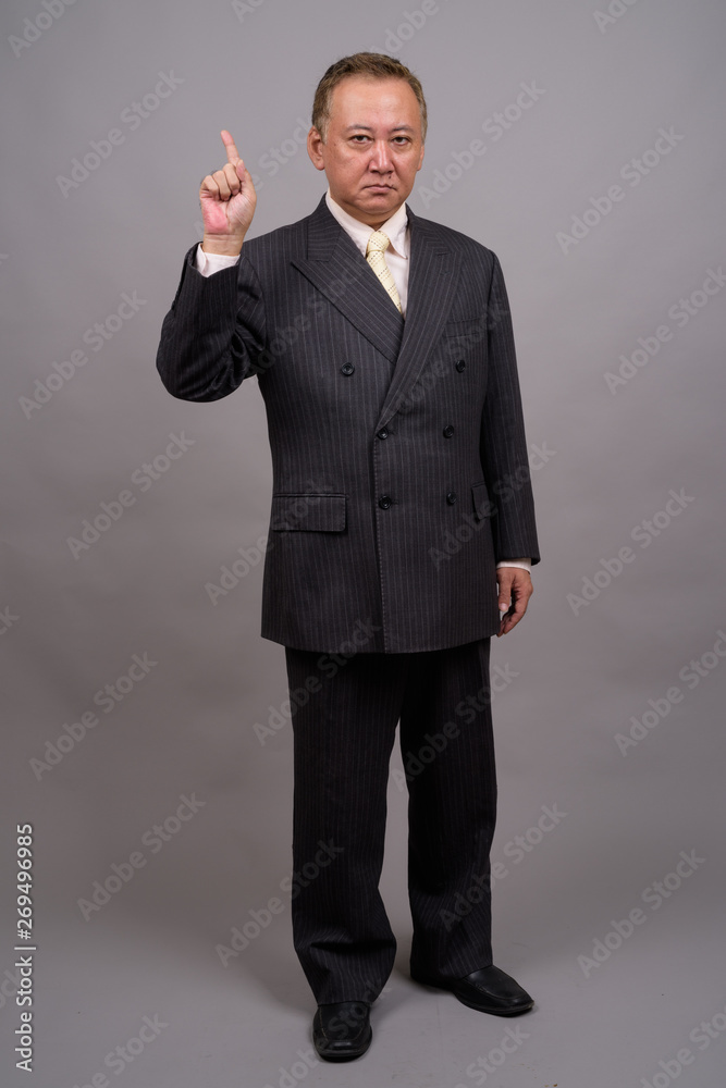 Portrait of mature Asian businessman against gray background Portrait of mature Asian businessman against gray background