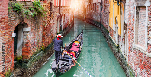 Canvas Venetian gondolier punting gondola through green canal waters of Venice Italy
