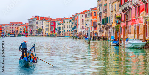 Venetian gondolier punting gondola through green canal waters of Venice Italy photo