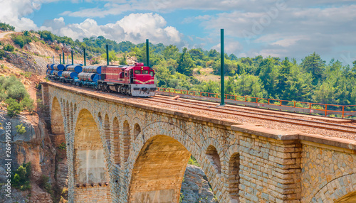 Red passenger diesel train moving at the bridge - Varda railway bridge, Adana Turkey photo