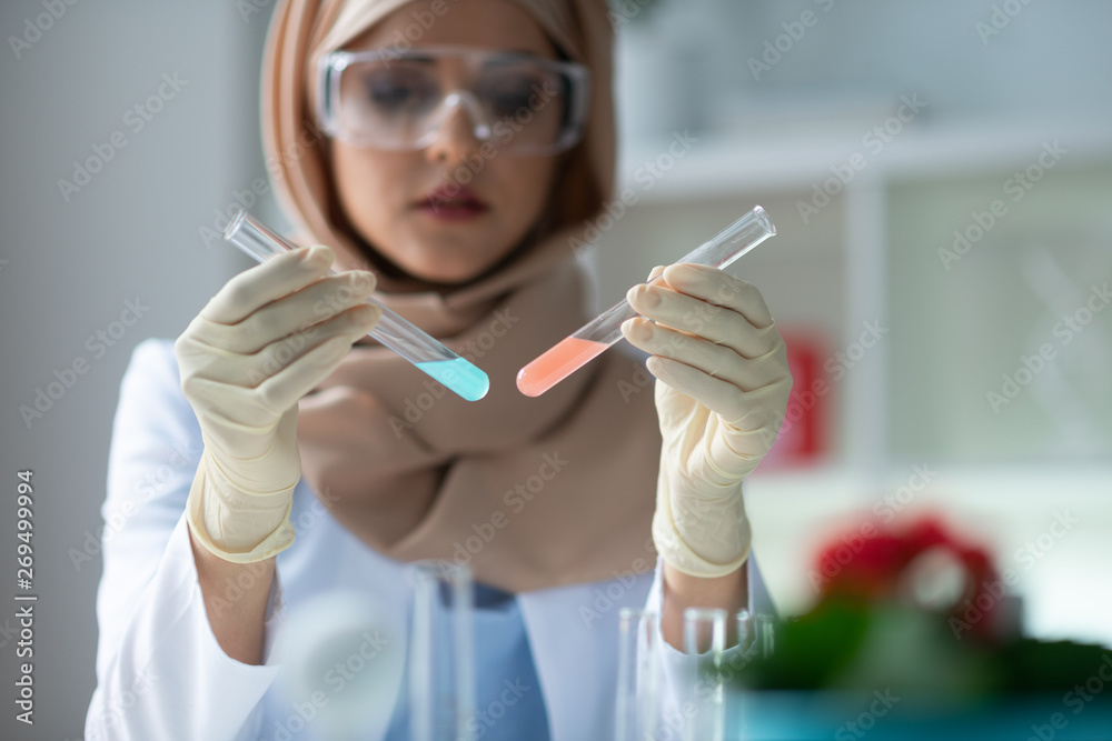 Chemist holding test tubes with pink and blue chemical agents Chemist holding test tubes with pink and blue chemical agents