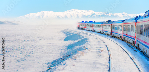 Red diesel train  East express  in motion at the snow covered railway platform - The train connecting Ankara to Kars - Turkey